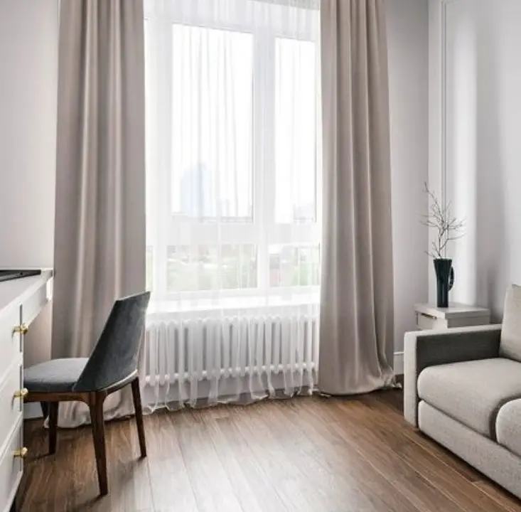 A room with a desk chair standing in front of the window